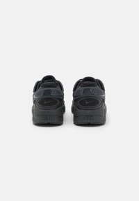 Nike-sneakers i mörkgrått med en texturerad gummisula, vadderad anklekoll och en framträdande "Air"- och logotypdetalj på hälen.