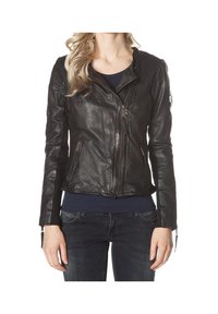 Femme portant une veste en cuir noire zippée en diagonale, associée à un jean foncé et un haut foncé, vue du cou aux hanches.