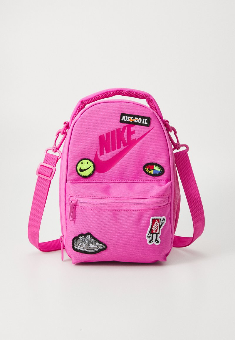 Mochila Nike rosa con compartimentos con cremallera, parches cosidos y un logotipo prominente. Correa ajustable, diseño compacto y tela duradera.