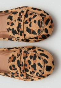 Mokasyny w cętki lamparta wykonane z materiału imitującego futro, z zaokrąglonym noskiem, przeszytym obrysem i małym paskiem zdobiącym przód buta.