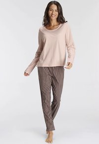 Lyserød langærmet top kombineret med brune bukser med striber. Stoffet virker blødt; bukserne har lodrette striber med spredte accenter.