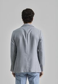 Blazer de cuadro de houndstooth azul claro, de un solo botón con solapas muescas, tejido texturizado, corte slim y doble apertura en la parte trasera.