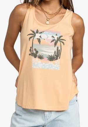 Vrouw draagt perzikkleurige tanktop met tropisch ontwerp van palmbomen, cactus, bloemen en oceaanscene, gecombineerd met lichtblauwe spijkerbroek.