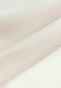 Helles cremefarbiges Gewebe mit einer glatten Textur, das eine subtile diagonale Webart und drei übereinanderliegende Falten aufweist. Ideal für Polsterungen oder Bekleidung.