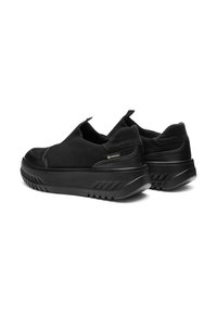Zapatos negros tipo slip-on con un acabado de ante suave y detalles texturizados. Cuentan con una suela de goma gruesa y resistente con un patrón de rayas distintivo.