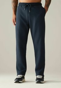Pantalones jogger de mezcla de algodón en azul marino con cinturilla elástica, cierre con cordón, bolsillos laterales y diseño de pierna tapered. Acentuados con detalles metálicos.