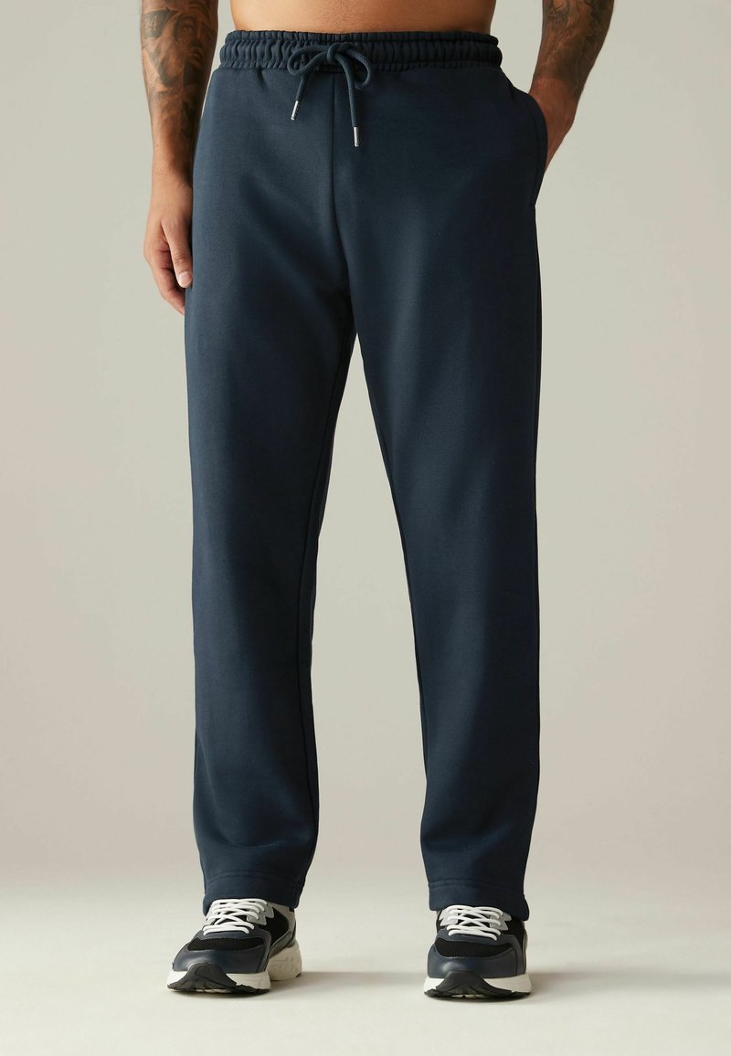 Pantalones jogger de mezcla de algodón en azul marino con cinturilla elástica, cierre con cordón, bolsillos laterales y diseño de pierna tapered. Acentuados con detalles metálicos.