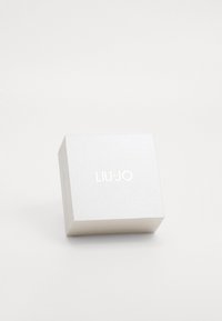 Scatola rettangolare bianca con superficie texturizzata, caratterizzata dal testo impresso "LIU JO" in argento, progettata per l'imballaggio.
