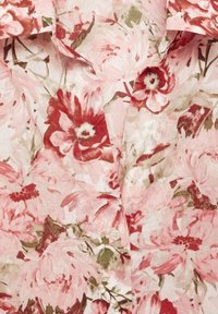 Blusa floreale con un motivo di fiori rosa e rossi su tessuto leggero, con colletto scollato e chiusura a un bottone sul davanti.
