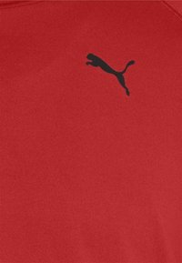 Rotes Sportshirt aus glattem Stoff mit schwarzem Puma-Logo. Kurze Ärmel und runder Halsausschnitt. Einfaches Design ohne Muster.