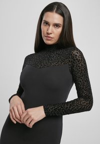 Pikkade varrukatega kleit, millel on must kere ja läbipaistvad leopardimustriga varrukad. Sile tekstuur, sobiv siluett ja kõrge kaelus.