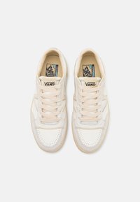 Hvit sneakers med beige detaljer, glatt skinnoverside, perforert tå, flate lisser og gummisåle. Merkevaren sin logo på tungen.