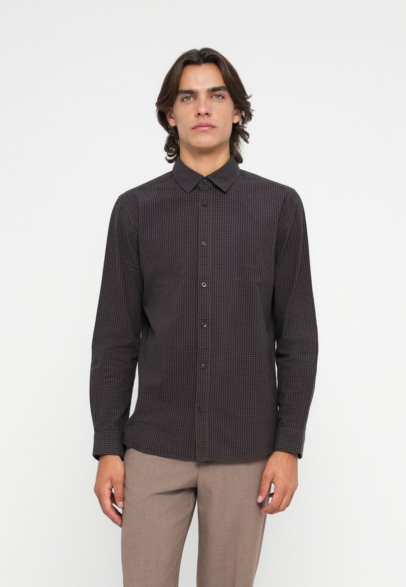 Hosszú ujjú ing, sötét kockás mintával, gombos gallérral és elöl gombokkal. Az anyag simának tűnik, enyhén fényes.