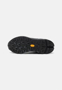 Black rubber outsole with aggressive traction pattern and orange branding detail, designed for durability and grip on various terrains.