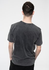 Charcoal gray, short-sleeve t-shirt with a soft, slightly textured finish and a crew neckline, displayed from the back.