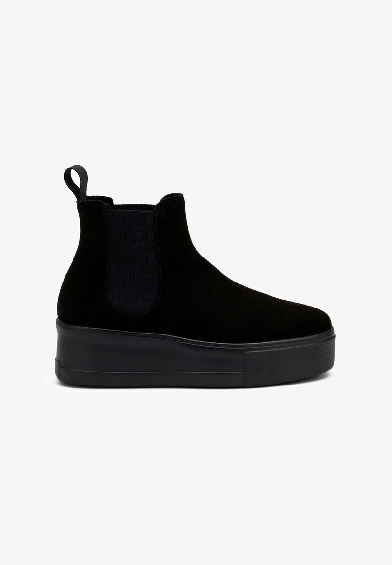 Botas de ante negras hasta el tobillo con paneles laterales elásticos, una pestaña de tirón y una suela de plataforma gruesa de goma negra. Textura suave con un detalle mínimo.