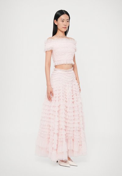 Lyserødt to-delt sæt med en cropped, off-shoulder top og en lang nederdel med lagdelte flæser og en struktureret overflade.