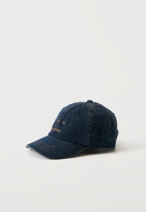 Gorra de béisbol de mezclilla azul oscuro con visera curva y texto dorado bordado en la parte frontal, descansando sobre una superficie blanca lisa.
