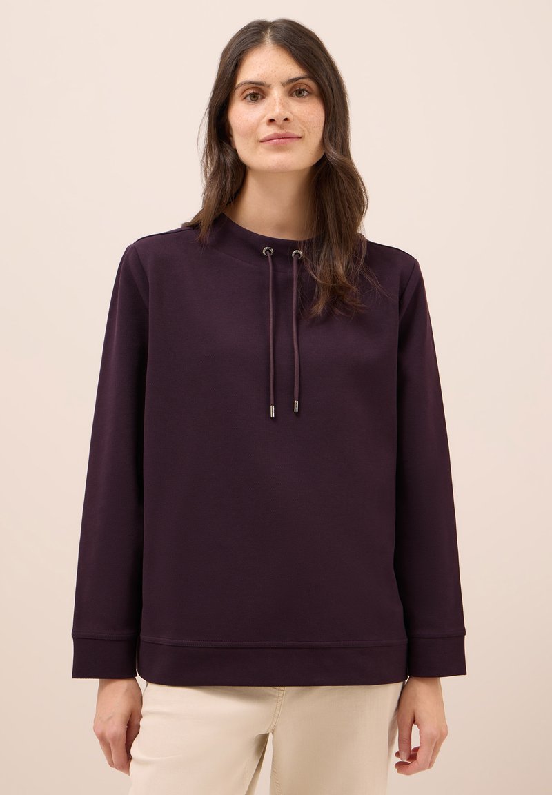 Diep paarse hoodie met hoge kraag, koordaccenten en lange mouwen. Zachte stof, ontspannen pasvorm, ribgebreide mouwen en onderrand.