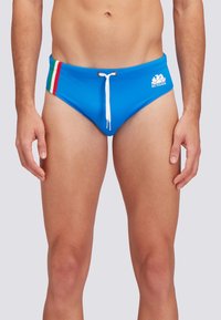 Pantaloni da bagno blu con cordoncino bianco, caratterizzati da strisce verdi, bianche e rosse sulla vita e un logo sul lato sinistro.