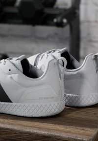 Harmaat urheilukengät, joissa on teksturoitu päällinen, geometrinen kuvio pohjassa ja "ZERO DEGREE DROP" -merkki sivussa.