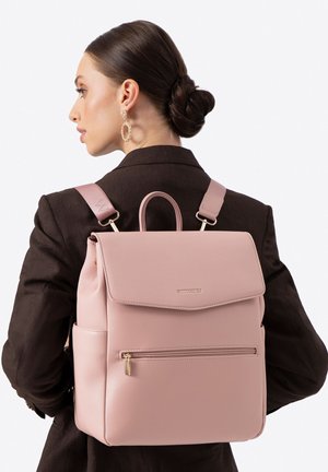Růžový kožený batoh se zavíráním na klopu, přední kapsou na zip a nastavitelnými popruhy. Hladká textura s detaily v provedení zlatého kovu.