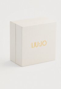Balts teksturētais kastīte ar magnētisko aizdari, priekšpusē ar reljefā zelta tekstu "LIU·JO". Kvadrātveida dizains.