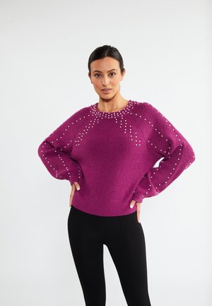 Lilla strikket sweater med rund hals, der har dekorative perle detaljer langs skuldrene og ærmerne. Lange, løse ærmer.