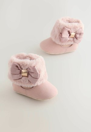 Pink booties with a soft faux fur cuff, featuring a large ribbed bow and a gold accent detail. Suede-like material, round toe shape.