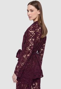 Vestaglia di pizzo malva con maniche lunghe, cintura in vita, motivi floreali e design testurizzato. Elegante con orlo smerlato.