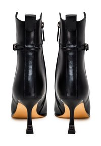 Bottines noires en cuir avec un design épuré, présentant une fermeture éclair, un bout pointu et un talon aiguille étroit.