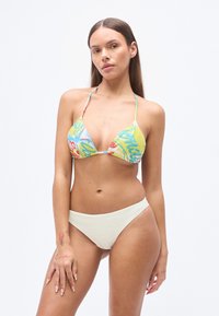 Έγχρωμο τοπ μπικίνι με τριγωνικά κύπελλα, με κίτρινο και μπλε σχέδιο. Συνδυάζεται με μονόχρωμα ανοιχτό μπεζ κάτω μέρος μπικίνι.