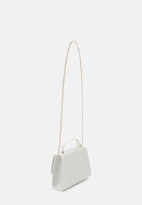 Petit sac à main blanc à la forme structurée, attaches dorées pour la poignée supérieure et longue bandoulière en chaîne dorée, présenté sur fond blanc uni.