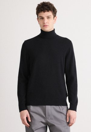 Schwarzer Rollkragenpullover mit langen Ärmeln, weicher Textur, seitlichen Schlitzen am Saum, getragen über grauen Hosen.