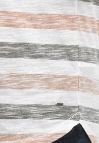 Camisa de rayas con líneas horizontales en blanco, gris y melocotón. Tejido suave con un dobladillo redondeado y una pequeña etiqueta tejida en la parte inferior.