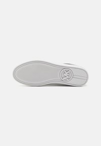 Weiße Sneakersohle aus strukturiertem Gummi, mit einem kreisförmigen Logo und einer glatten, abgerundeten Kante. Subtile Linien über die Sohlenoberfläche.