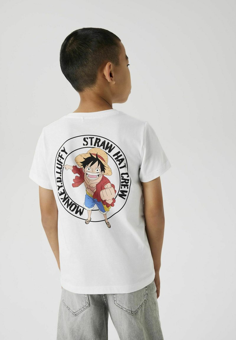 T-shirt en coton blanc avec un design imprimé coloré d'un personnage portant un chapeau de paille, avec la légende "Monkey D. Luffy Straw Hat Crew."