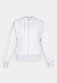 Dragkedja i ljusgrå fleece, med huva, framfickor och tre-rands detaljer på ärmarna. Diskret logotyp på bröstet.