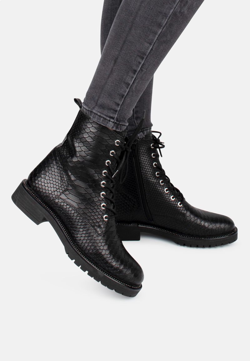 Bottes de cheville noires avec une texture en cuir de serpent, dotées d'œillets argentés, de lacets noirs et d'une semelle en caoutchouc robuste. Finition avec des coutures détaillées.