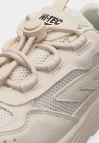 Uvećani prikaz bež Hi-Tec tenisice s mrežastim panelima, slojevima od antilopa i elastičnim vezicama osiguranim okruglim kopčom.