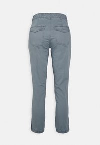 Grå byxor med elastisk midja, raka ben, två bakfickor och rynkade muddar vid fållen. Slät tygstruktur.