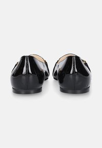 Ballerine in vernice nera con punta arrotondata e tacco basso e piatto. Decorate con una semplice cucitura e piccoli accessori metallici.