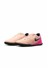 Nike performance shoes with a light pink upper, black accents, and a pink gradient heel. Textured surface and rubber sole for traction.