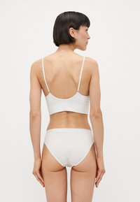 Bralette blanche à côtes et culottes assorties, avec des bretelles ajustables, un design sans couture et une texture douce pour le confort.