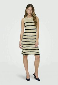 Vestido de punto sin mangas con un cuerpo beige y rayas horizontales negras, que presenta una silueta ajustada y un dobladillo a la altura de la rodilla.