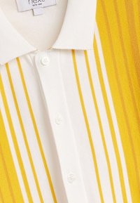 Gelb-weiß gestreiftes Poloshirt mit geripptem Kragen, ausgestattet mit einer Knopfleiste und strukturierter Stoffoberfläche.