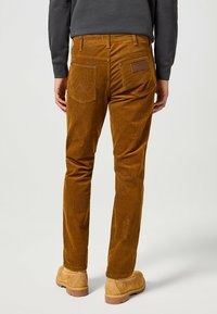 Bruine corduroy broek met een slim fit, achterzakken met een opvallend stikselpatroon en een gestructureerde oppervlakte. Leren merketiket op de tailleband.