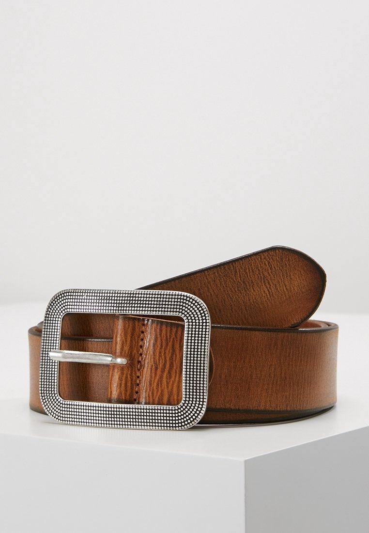 Ceinture en cuir marron enroulée avec une grande boucle rectangulaire argentée présentant un motif texturé en pointillé, reposant sur une surface blanche sur fond uni.