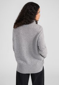 Grauer Strickpullover mit geripptem Saum und Bündchen, im entspannten Schnitt. Weicher Stoff, lange Ärmel und hoher Kragen.