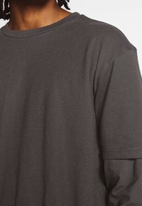 Dark gray cotton t-shirt with a crew neckline and short sleeves. Smooth texture with a relaxed fit. No visible patterns or accents.